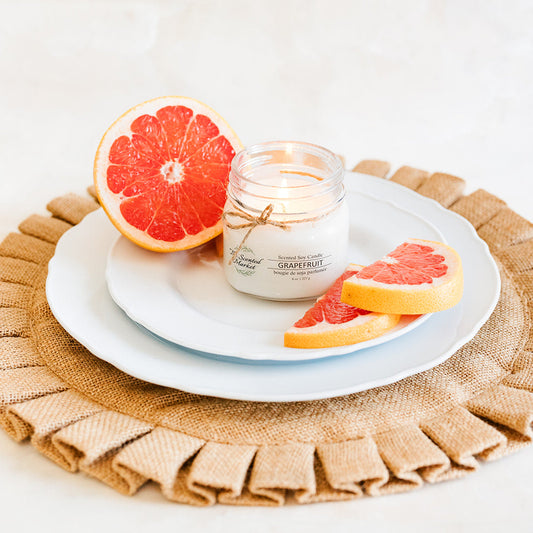 Candle with grapefruit slices on a white plate on a textured surface