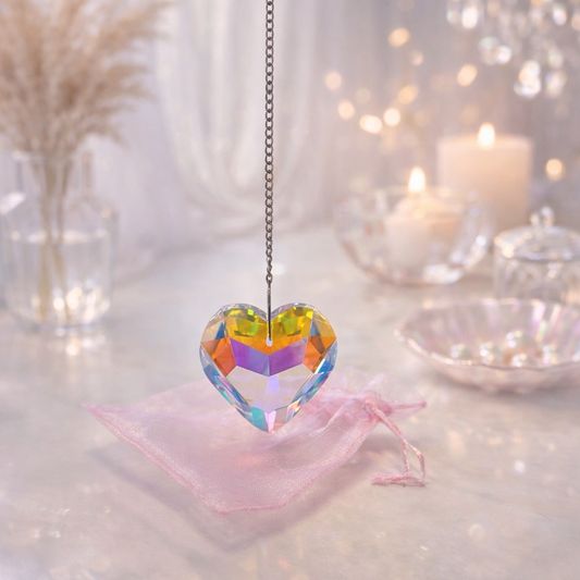 Heart-shaped colorful crystal pendant on a chain against a soft, blurred background.