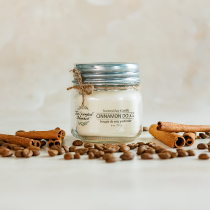Jar of cinnamon dolce body butter with cinnamon sticks and coffee beans on a light background