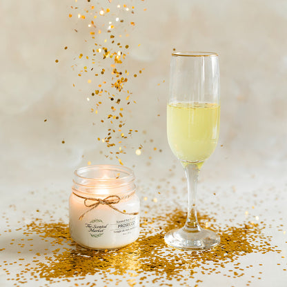 Glass of champagne and candle with gold confetti on a light background