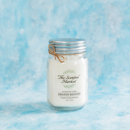 Candle in a mason jar with 'The Scented Market' label on a blue textured background