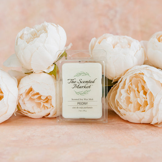 Wax melt packaging with 'The Scented Market' branding surrounded by white flowers on a soft pink background