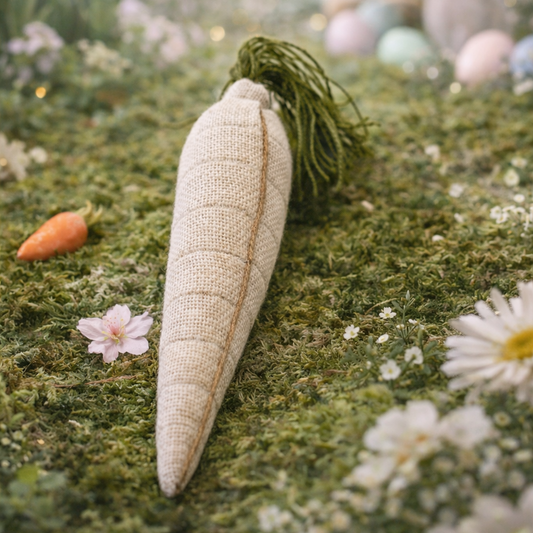 Decorative carrot on a grassy surface with flowers and a blurred bunny in the background