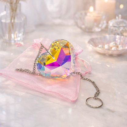 Heart-shaped crystal pendant on a pink fabric with blurred decorative background