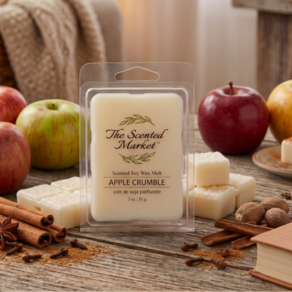 A packaged wax melt from The Scented Market labeled Apple Crumble, shown in a clear clamshell package on a rustic wooden table with apples, cinnamon sticks, cloves, and a cozy indoor background.