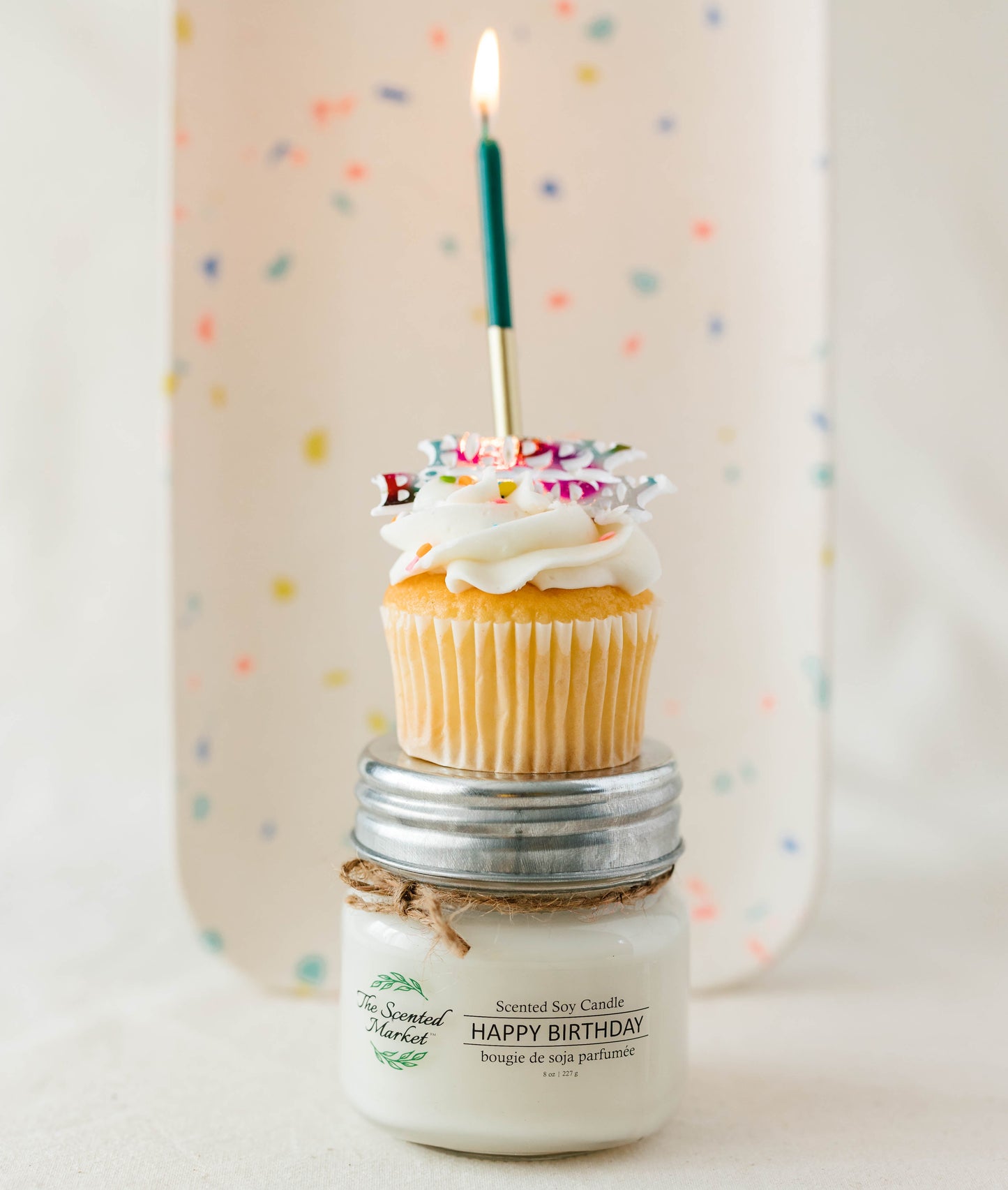Candle with a cupcake and lit candle on top against a polka dot background